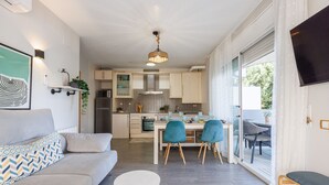 Una sala de estar moderna con un sofá, una mesa de comedor con sillas y una cocina al fondo.