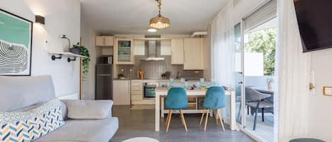 Una sala de estar moderna con un sofá, una mesa de comedor con sillas y una cocina al fondo.