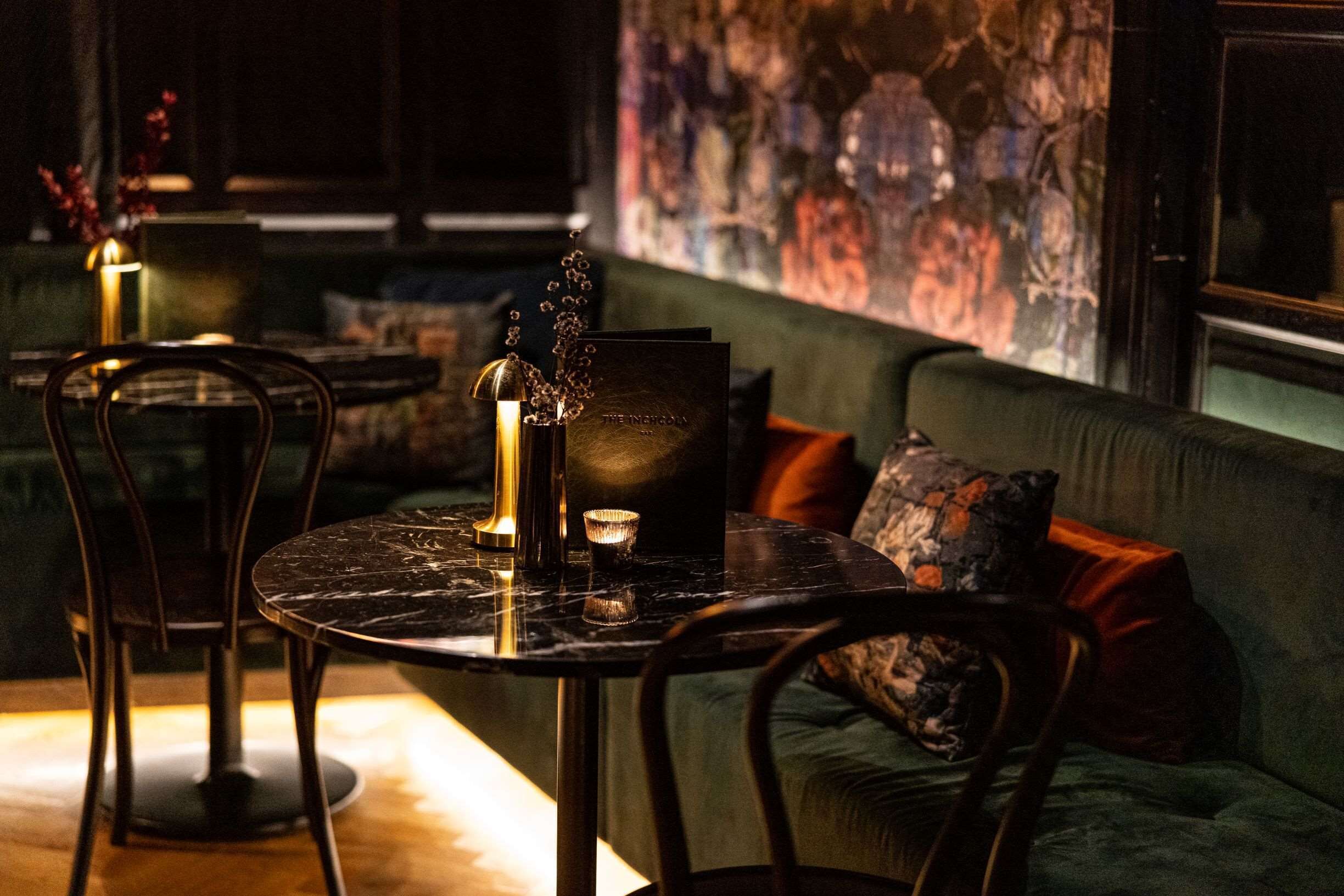 Une pièce faiblement éclairée, avec une table ronde, des chaises et un canapé agrémenté de coussins.