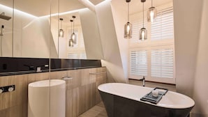A modern bathroom with a freestanding bathtub, a large mirror, and pendant lighting. - The Inchcolm by Ode Hotels (Spring Hill)