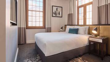Habitación de hotel con una cama grande, una mesita de noche con una lámpara y un cuadro en la pared.
