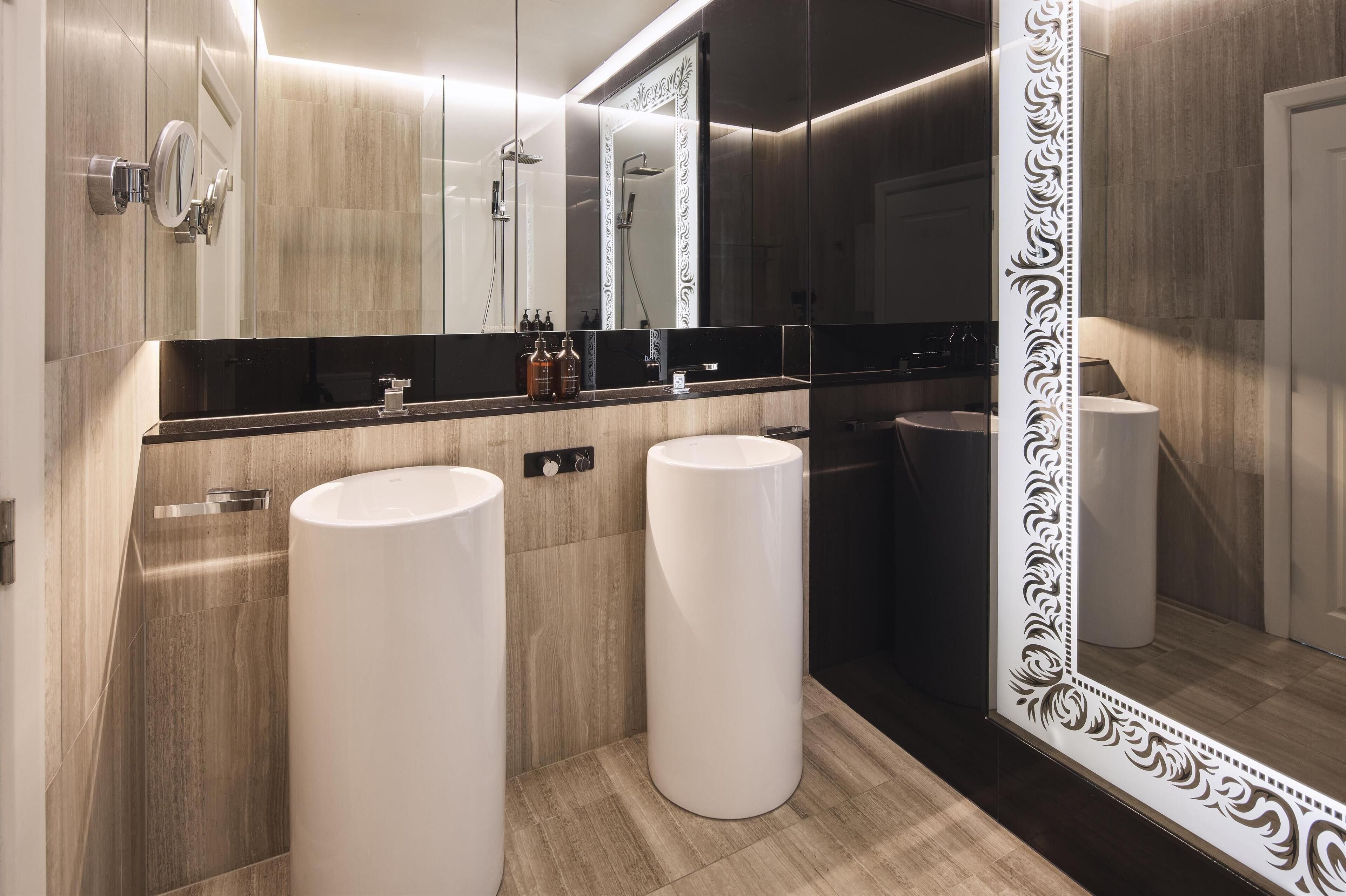Une salle de bain moderne avec deux lavabos, un grand miroir et une douche.