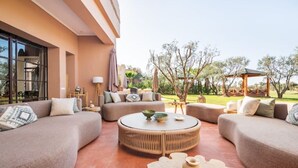Ein moderner Außenbereich zum Verweilen mit Sofas, einem runden Tisch und einer Pergola.