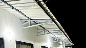 A building with a covered porch, large windows, and a metal railing. - Riverstone Camps and Resorts (Yamkeshwar)