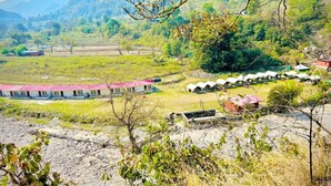 A hotel with multiple rooms, a red-roofed building, and a mountainous backdrop. - Riverstone Camps and Resorts (Yamkeshwar)