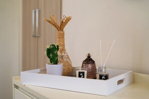 A white tray with a cactus, a woven vase, a candle, and a glass jar with a label. - Milos Apartments  (Faistos)