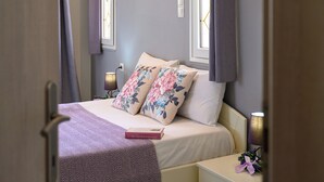 A bedroom with a bed, nightstands, and a window with curtains. - Milos Apartments  (Faistos)