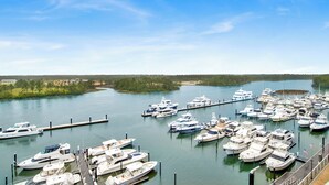 A marina with numerous boats docked at piers, surrounded by greenery and a clear sky. - Waterfront 2BR at The Wharf • Sleeps 6 • Amazing Views • Oasis Pool (Orange Beach)