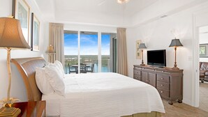 A hotel room with a large bed, a television, a dresser, and a balcony with a view. - Waterfront 2BR at The Wharf • Sleeps 6 • Amazing Views • Oasis Pool (Orange Beach)