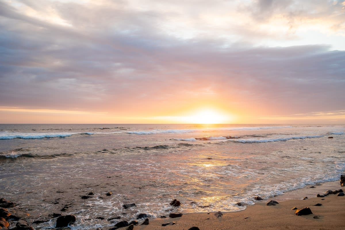 Une plage avec des vagues et un coucher de soleil.