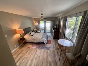 Quarto com cama, abajures, uma mesinha e vista para o exterior.