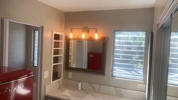 A bathroom with a red appliance, a sink, a mirror, and a window.