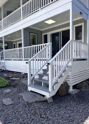 Un bâtiment à deux étages, à l’extérieur blanc, doté d’un porche couvert avec des balustrades blanches et d’un escalier menant à l’étage supérieur.