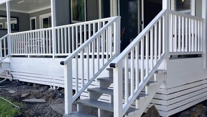 Una casa de dos pisos con un porche cubierto y una escalera que conduce al nivel superior.