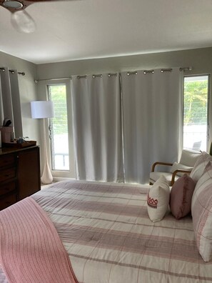 Une chambre à coucher avec un lit, une commode, une lampe et une fenêtre avec des rideaux.