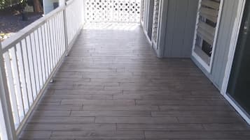 A covered wooden deck with a white railing and lattice screen.