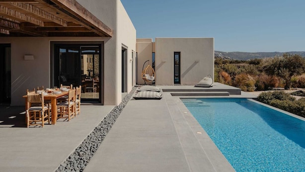 A modern outdoor pool area with a dining setup and seating.