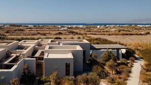 A modern villa with a rooftop terrace, a swimming pool, and a view of the coastline.