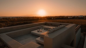 A rooftop terrace with a view of the sunset over a landscape.