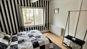 A bedroom with a checkered bedspread, a window with curtains, a radiator, and a hanging chair. - Cinematic Experience in fully renovated apartment near Montmartre - Paris (Paris)