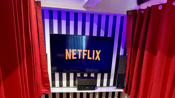 A cozy room with a large flat-screen TV displaying "NETFLIX," a comfortable sofa, a small coffee table, and red curtains. - Cinematic Experience in fully renovated apartment near Montmartre - Paris (Paris)
