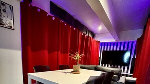 A modern conference room with a white table, black chairs, red curtains, and a large flat-screen TV. - Cinematic Experience in fully renovated apartment near Montmartre - Paris (Paris)