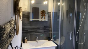 Une salle de bain moderne avec une douche à l’italienne en verre, un lavabo blanc et un miroir au-dessus.