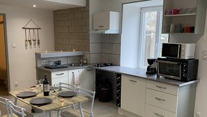 Une cuisine moderne avec un coin repas, comprenant un four encastré, un four à micro-ondes et une machine à café.