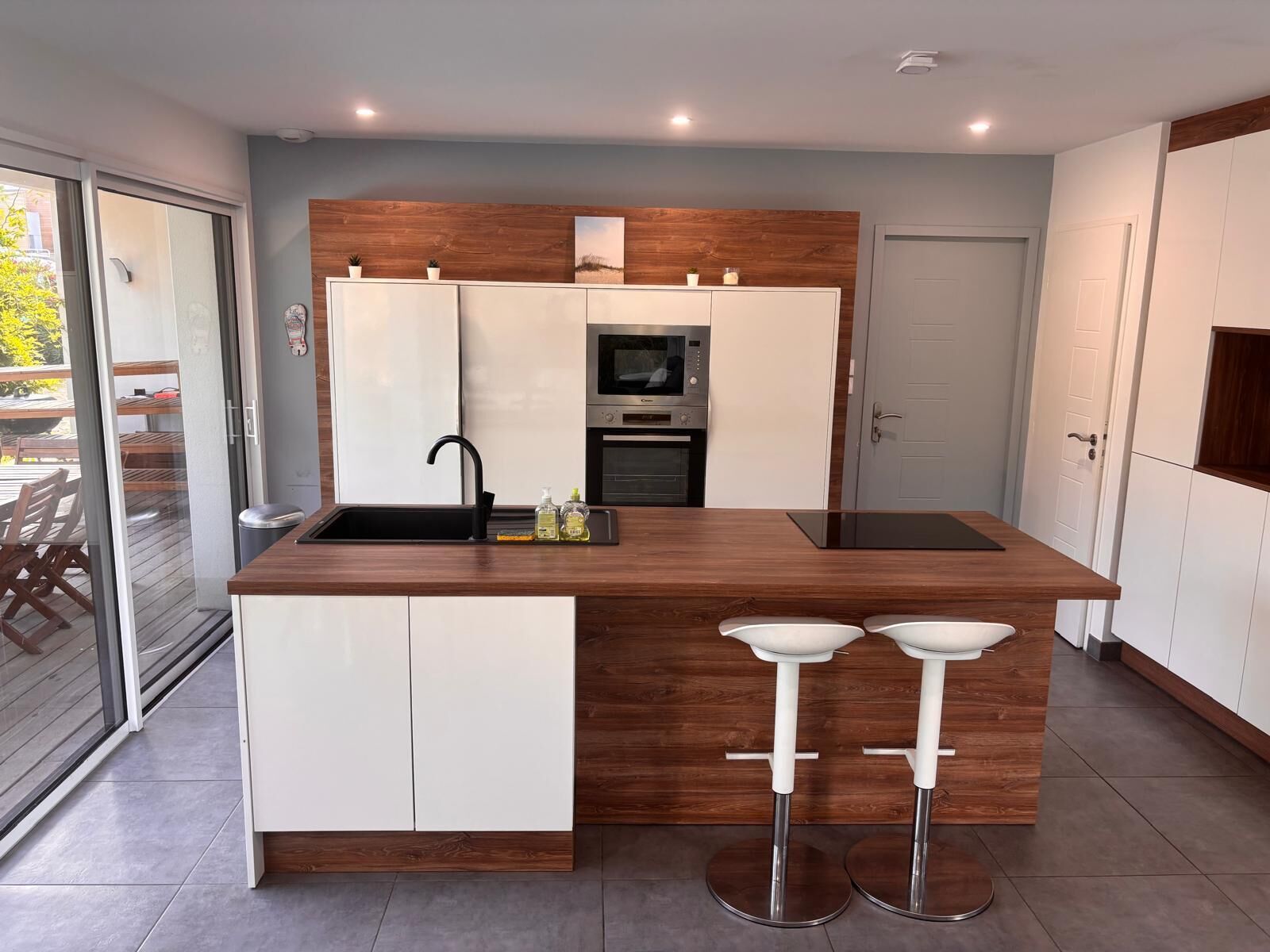 Een moderne keuken met een centraal eiland, witte kasten en roestvrijstalen apparatuur.