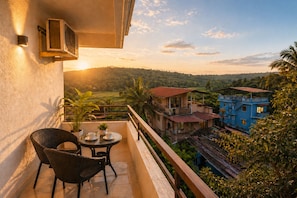 A balcony with a table and chairs, overlooking a scenic landscape with buildings and greenery. - Maple Leaf Residency Homes Calangute (Calangute)