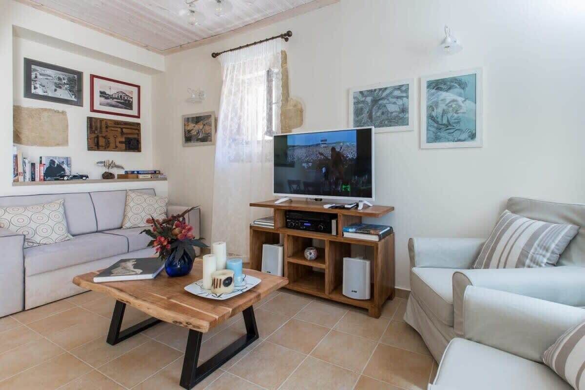 A living room with a TV, sofas, a coffee table, and wall art.