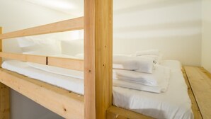 A wooden bunk bed with white bedding in a room with white walls and a wooden floor. - Cosy Box @ Boxhagener Platz (Berlin)