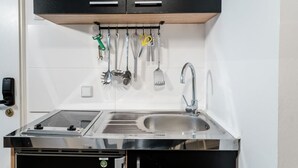 A modern kitchen with a stainless steel sink, a built-in stove, and a hanging utensil rack. - Cosy Box @ Boxhagener Platz (Berlin)
