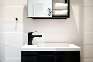 A modern bathroom with a white sink, black faucet, and a mirror above it. - Cosy Box @ Boxhagener Platz (Berlin)