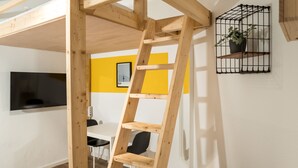 A wooden ladder in a room with a yellow wall, a mounted TV, and a black shelf with a plant. - Cosy Box @ Boxhagener Platz (Berlin)