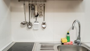 A kitchen with a stainless steel sink, a stove, and various utensils hanging on the wall. - Cosy Box @ Boxhagener Platz (Berlin)