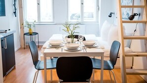 A modern dining area with a white table set for four, black chairs, and a vase with flowers. - Cosy Box @ Boxhagener Platz (Berlin)