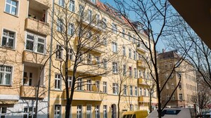 A multi-story building with balconies, parked cars, and a yellow van. - Cosy Box @ Boxhagener Platz (Berlin)