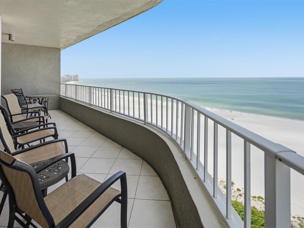 A balcony with a curved railing overlooking a beach.