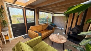 A cozy room with a wooden ceiling, a sofa, a small round table, and a fireplace.
