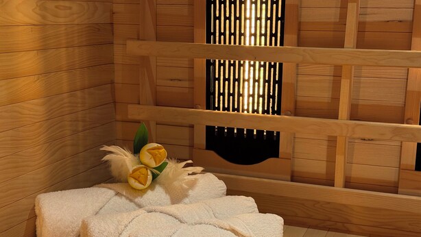 A wooden cabin-style room with a wooden floor, a bed with white fluffy bedding, and a decorative arrangement of yellow flowers and green leaves.