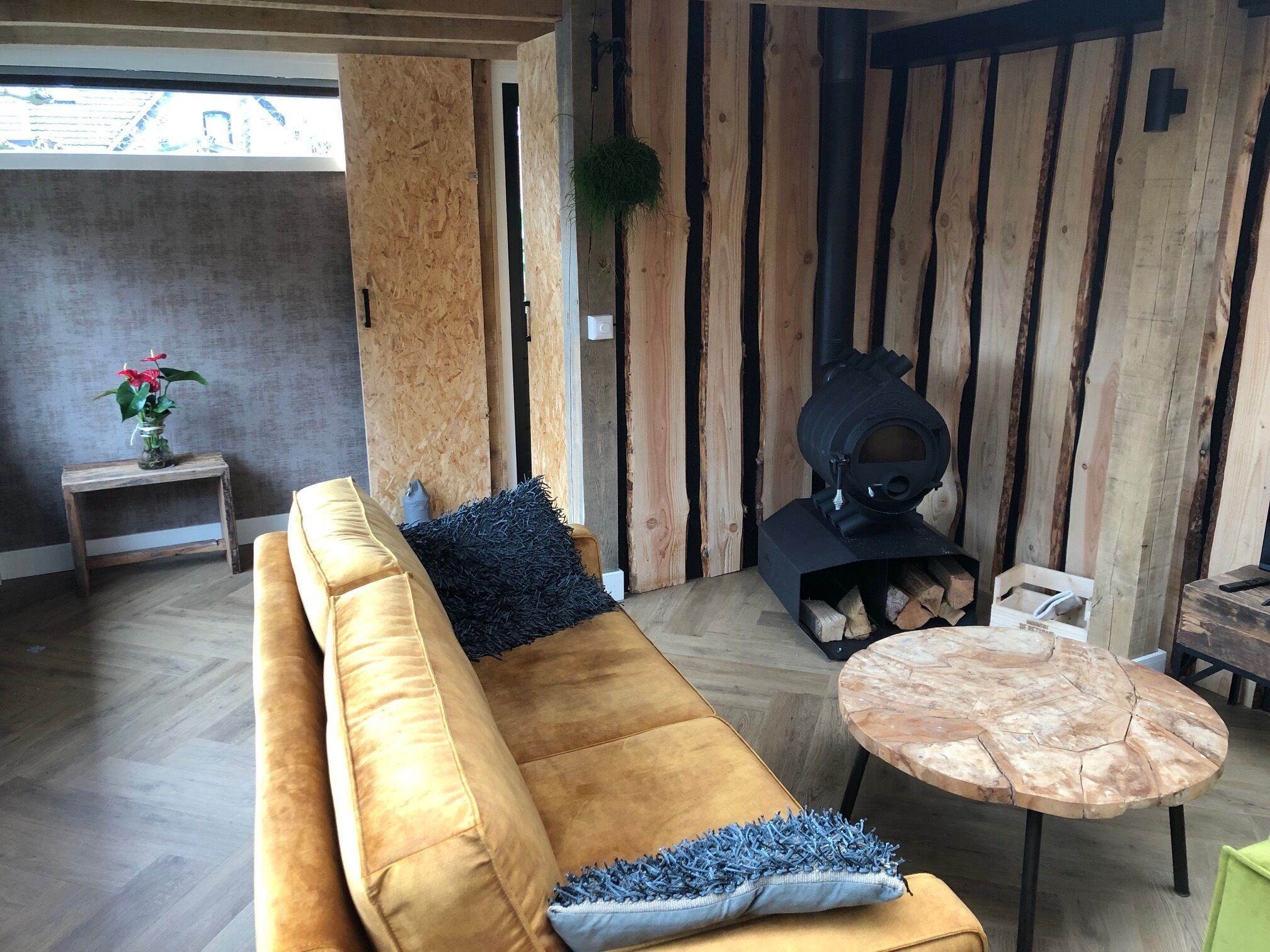 Ein modernes Wohnzimmer mit einer Wand aus Holzpaneelen, einer Couch, einem runden Couchtisch und einem Kamin.
