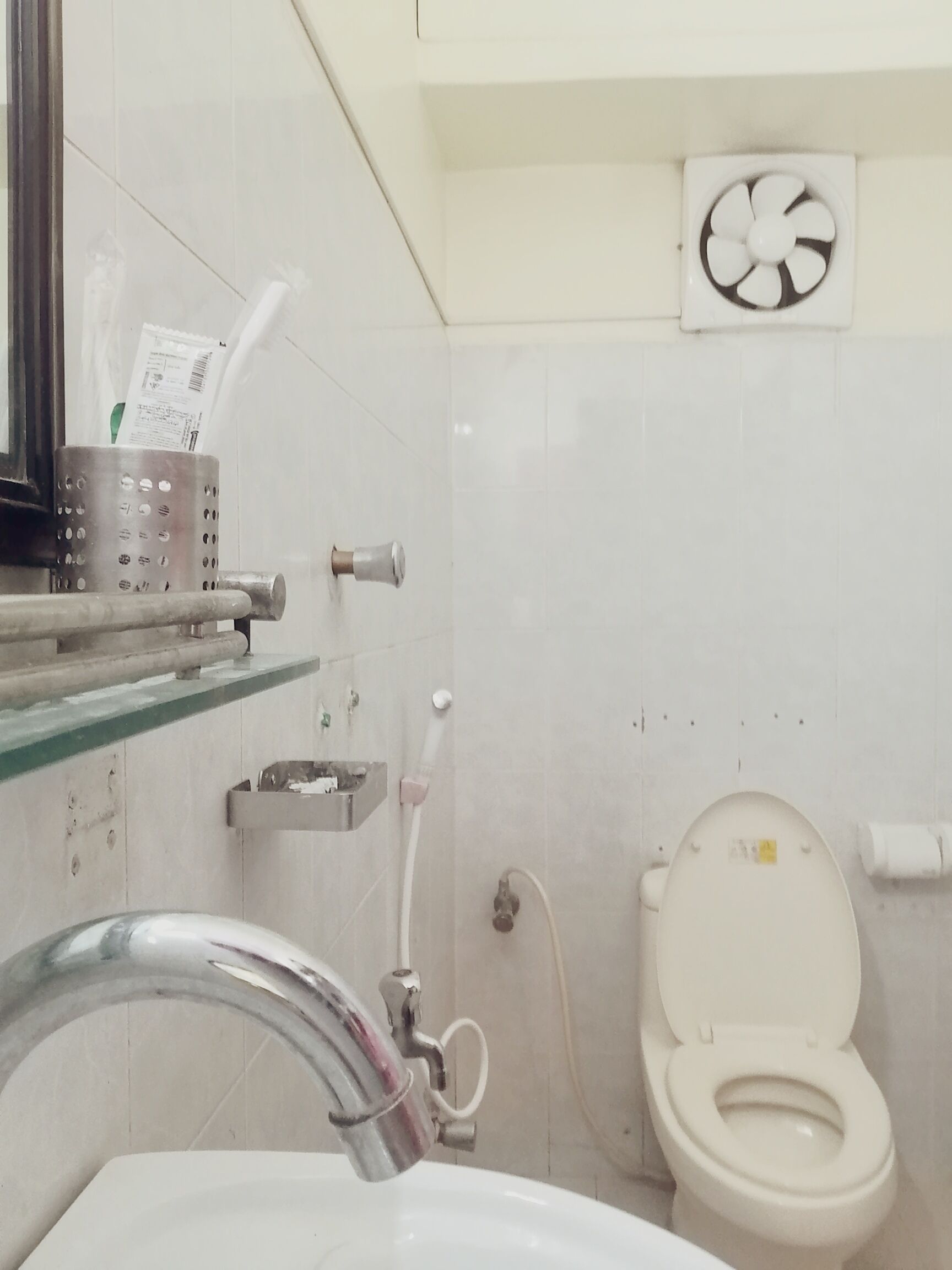 A bathroom with a toilet, sink, and a hand dryer.