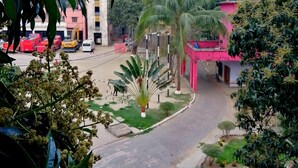 A residential area with a curved road, palm trees, and a building with a pink facade. - Hotel Hoque Tower International (Chittagong)