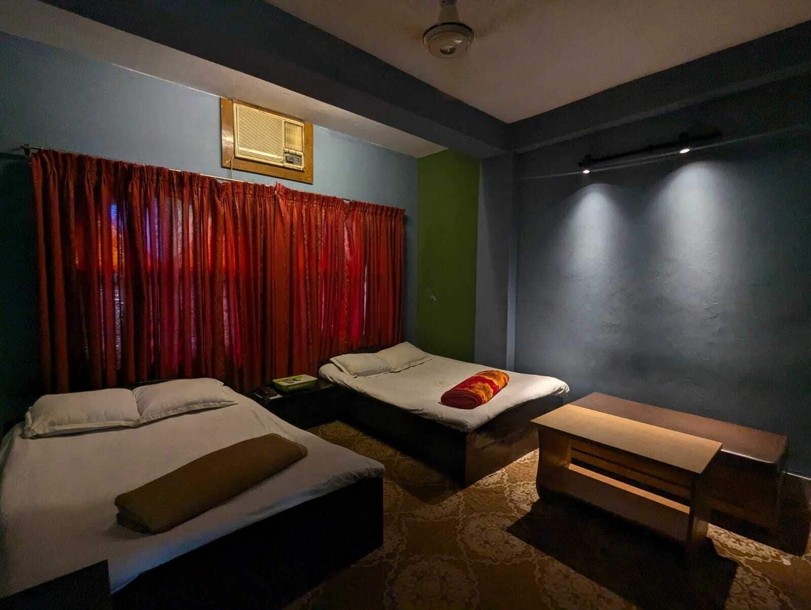 Una habitación con dos camas, un banco y un ventilador de techo.