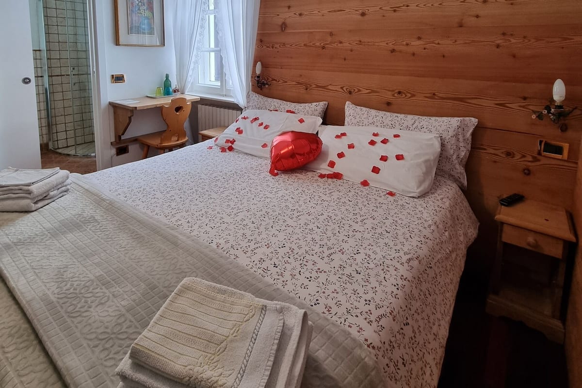 A cozy bedroom with a wooden headboard, a bed with floral bedding, and a bedside table with a lamp.