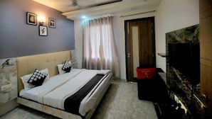 Un dormitorio con cama, ventilador de techo, televisor y una puerta.