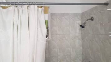 Un espacio de ducha con cortina, paredes de azulejos y un cabezal de ducha de mano.
