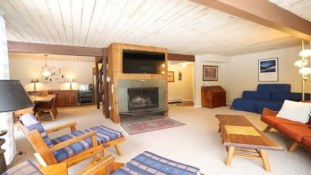 Una sala de estar acogedora con chimenea, muebles de madera y un sofá azul.