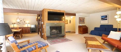Una sala de estar acogedora con chimenea, muebles de madera y un sofá azul.